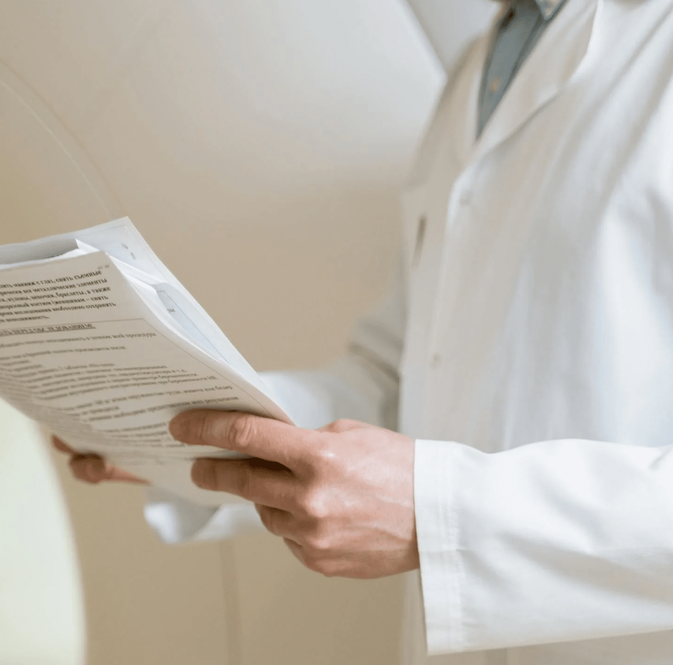 Gydytojas laiko medicininius dokumentus ir peržiūri tyrimų rezultatus, iliustruojant įvairius klinikoje atliekamus tyrimus ir procedūras.